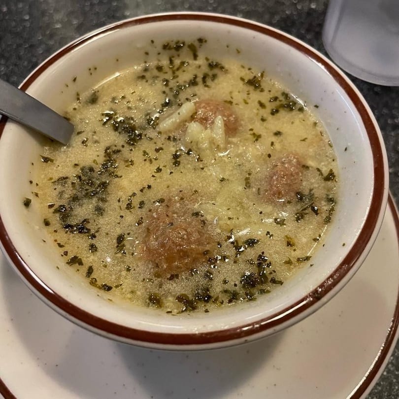 A bowl of creamy soup with meatballs, pasta, and green herbs, served at George's Shish Kebab.