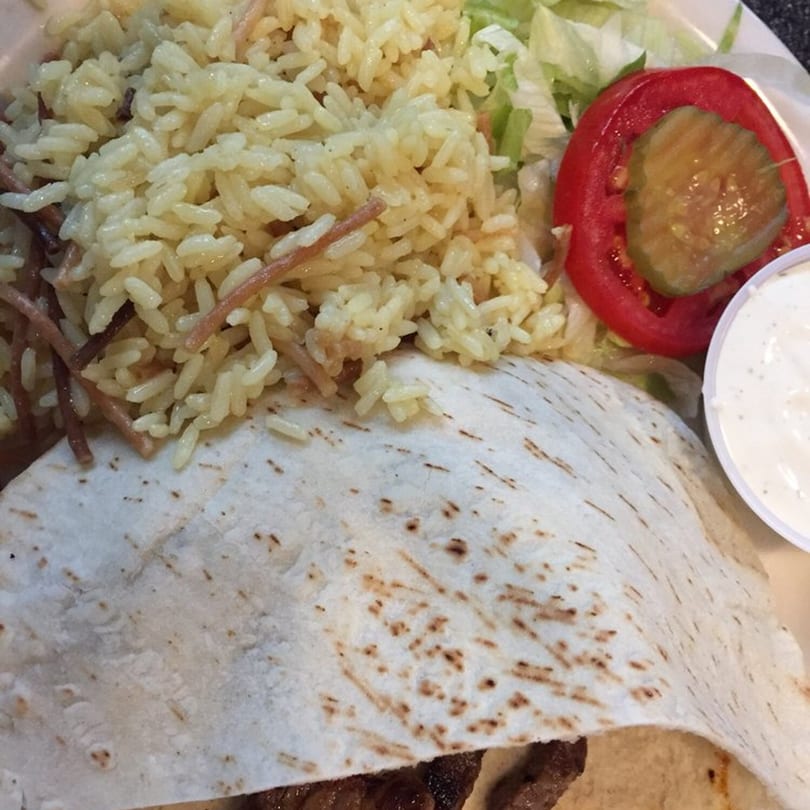 George's Shish Kebab plate with rice, salad, tomato, pickle, and a kebab wrapped in pita.